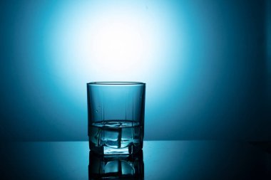 Mavi zemin üzerinde su olan bir bardak..