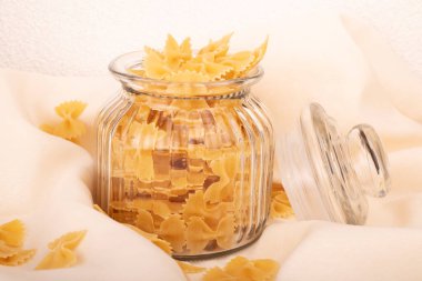 Çeşitli çiğ makarnaların yakın çekimi. Beyaz masada kompozisyon. Kavanozda çiğ makarna. Seçici odak.