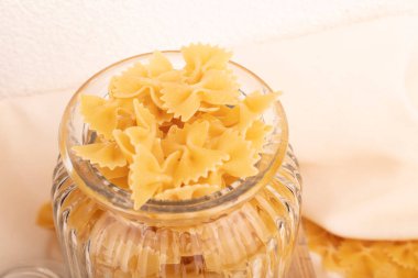 Çeşitli çiğ makarnaların yakın çekimi. Beyaz masada kompozisyon. Kavanozda çiğ makarna. Seçici odak.