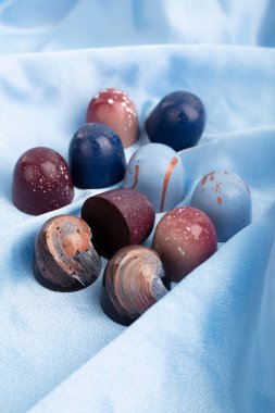 El yapımı top şeklinde çikolatalı şekerler, yasemin çiçekleriyle süslenmiş hafif bir arka planda bir el yapımı kutuda.