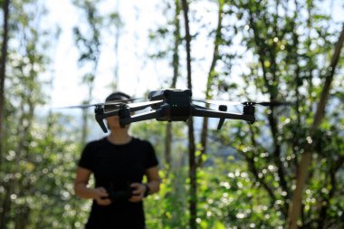 People remote control a flying drone in summer forest