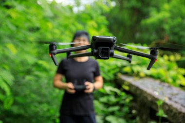 People remote control a flying drone in summer forest
