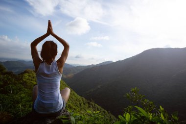 Dağ tepe uçurumun kenarında güneşin doğuşunu meditasyon yoga kadın