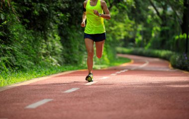 Güneşli tropik park yolunda koşan fitness kadını