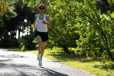 Güneşli tropik park yolunda koşan fitness kadını