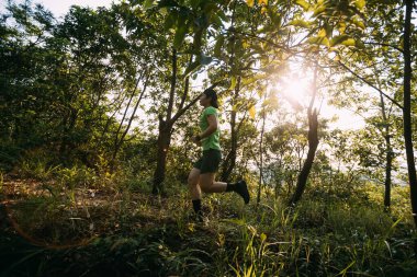 Trail runner running in summer forest trail