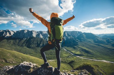 Başarılı bir kadın sırt çantalı dağ zirvesinde yürüyüş yapıyor.