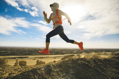 Çöl tepesinde koşan kadın koşucu.