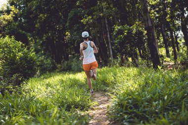Woman trail runner running at tropical forest mountain peak