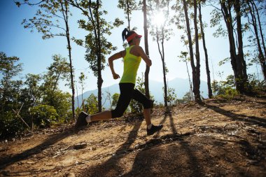 Woman trail runner running at tropical forest mountain peak