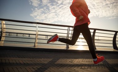 Fitness kadın koşucusu deniz kenarındaki köprüde koşuyor.