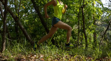 Trail runner running in summer forest trail