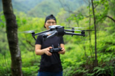 People remote control a flying drone in summer forest