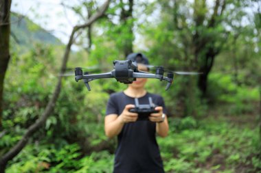 People remote control a flying drone in summer forest