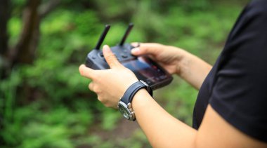 People remote control a flying drone in summer forest
