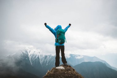 Kadın yürüyüşçü, dağın tepesindeki uçurumun keyfini çıkar. Tibet 'teki kar kaplı dağlara bak.