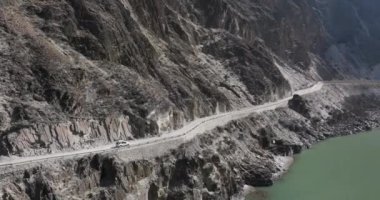 Dağlardaki yolda giden arabanın hava görüntüsü.