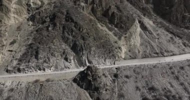 Dağlardaki yolda giden arabanın hava görüntüsü.