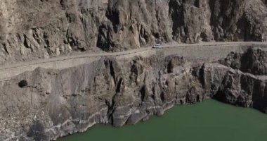 Dağlardaki yolda giden arabanın hava görüntüsü.