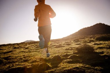 Yüksek irtifada dağ zirvesinde koşan kadın koşucu.