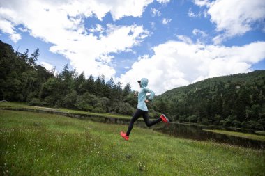 Güzel otlaklarda koşan kadın koşucu.