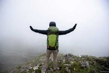 Dağın tepesinde sırt çantalı bir kadın.