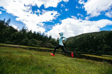 Güzel otlaklarda koşan kadın koşucu.
