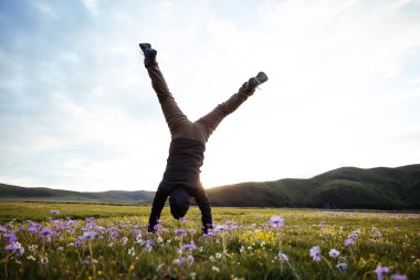 Yüksek rakımlı dağ çayırında bir handstand yapıyor kadın yürüyüşçü