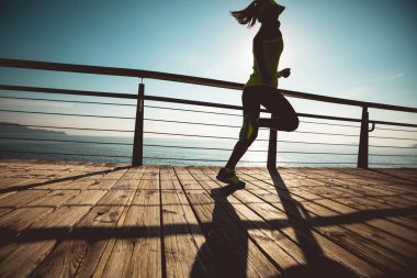 Sahil sahil üzerinde gündoğumu sırasında çalışan sportif kadın runner