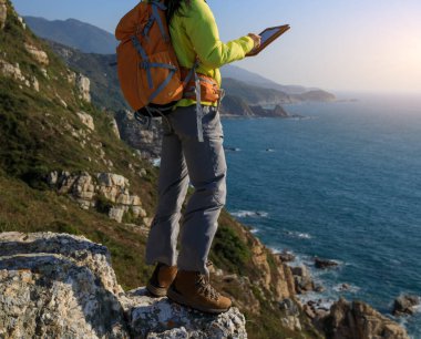 Genç kadın uzun yürüyüşe çıkan kimse kullanarak dijital tablet Seaside, yürüyüş sırasında 