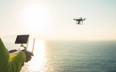 Uzaktan kumandalı siluet güneş doğarken deniz üzerinde fotoğraf çeken uçan bir dron. 