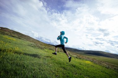 Yüksek irtifada koşan, çiçekli dağlarda koşan kadın koşucu.