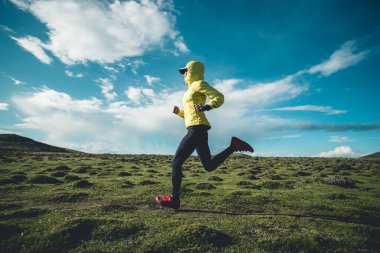 Yüksek irtifada dağ zirvesinde koşan kadın koşucu.