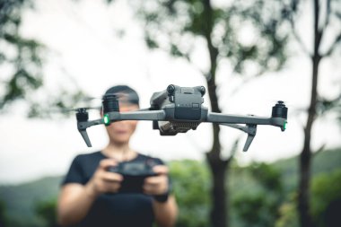 People remote control a flying drone in summer forest