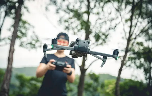 People remote control a flying drone in summer forest