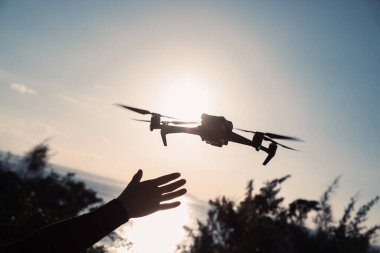 Gün doğumunda fotoğraf çeken uçan dron silueti.