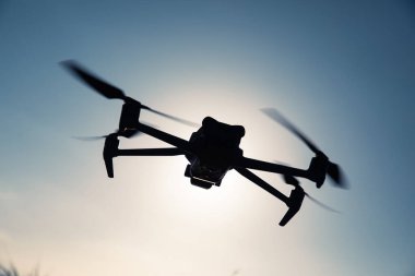 Gün doğumunda fotoğraf çeken uçan dron silueti.