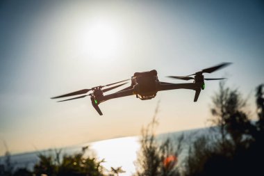 Gün doğumunda fotoğraf çeken uçan dron silueti.