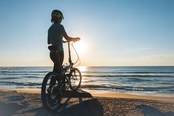 在日出海滨路上骑折叠自行车 — 图库照片
