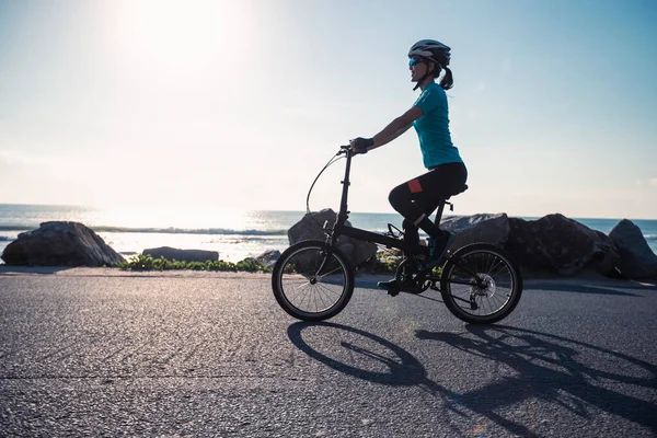 日当たりの海岸道路で折りたたみ自転車に乗る — ストック写真