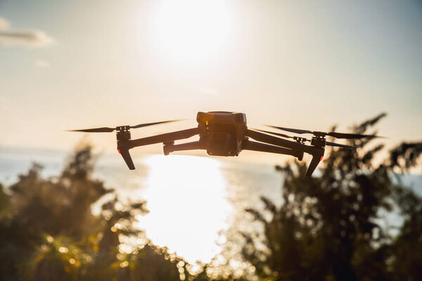 Silhouette of flying drone taking photo over sunrise
