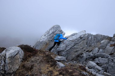 Tibet 'te dağın tepesine tırmanan bir kadın yürüyüşçü