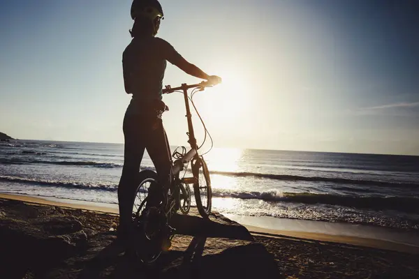 在日出海滨路上骑折叠自行车 — 图库照片