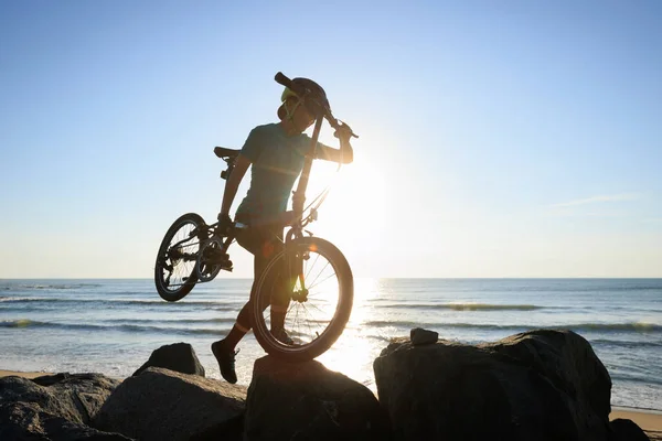 日出海滨背着可折叠自行车的女人 — 图库照片