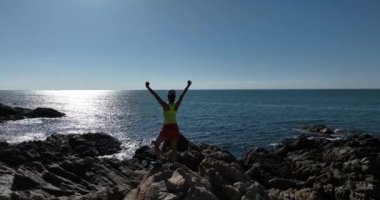 Denizde kayalıklarda sportif bir kadın.