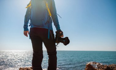 Gün doğumunda deniz kenarında kameralı fotoğrafçı  