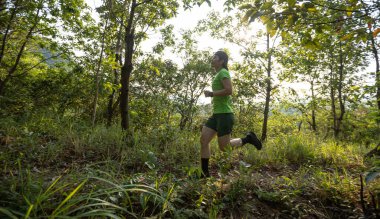 Woman trail runner running at tropical forest mountain peak