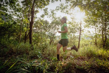 Woman trail runner running at tropical forest mountain peak