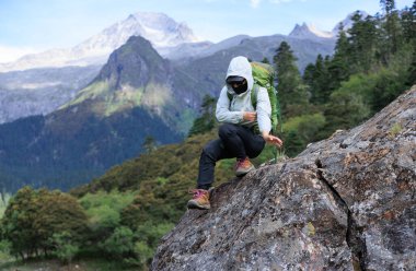 Tibet 'te dağın tepesine tırmanan bir kadın yürüyüşçü