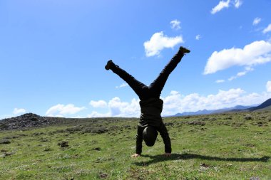 Yüksek rakımlı dağ çayırında bir handstand yapıyor kadın yürüyüşçü